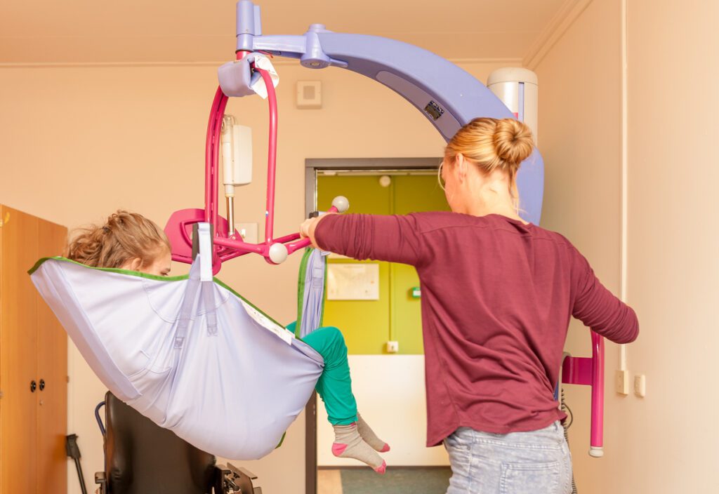 A disabled child in a wheelchair being cared for by a voluntary care worker